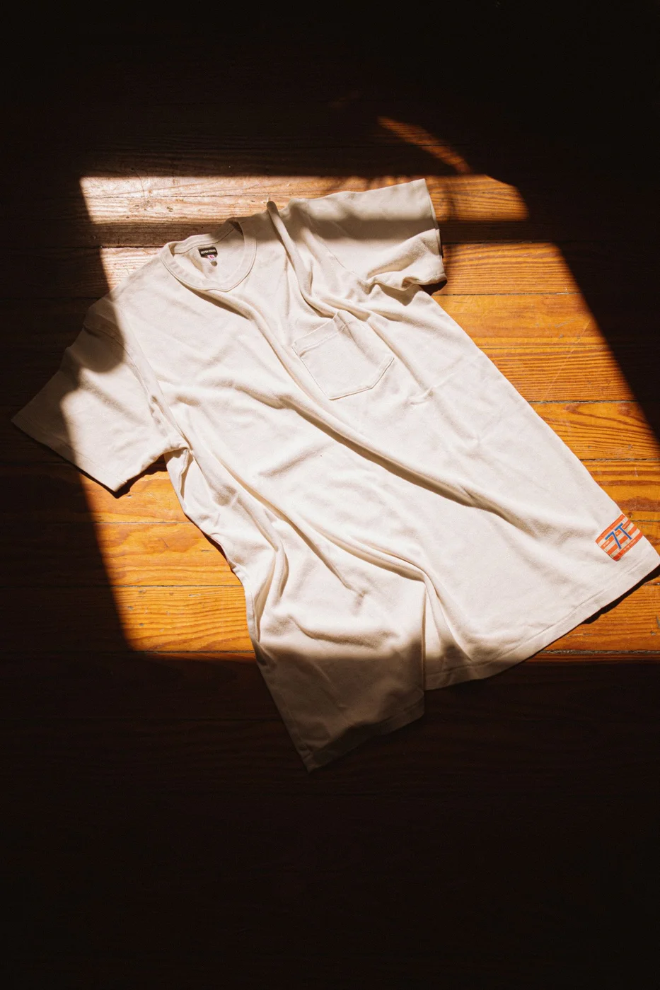 White T-Shirt in Sunlight on Wooden Floor