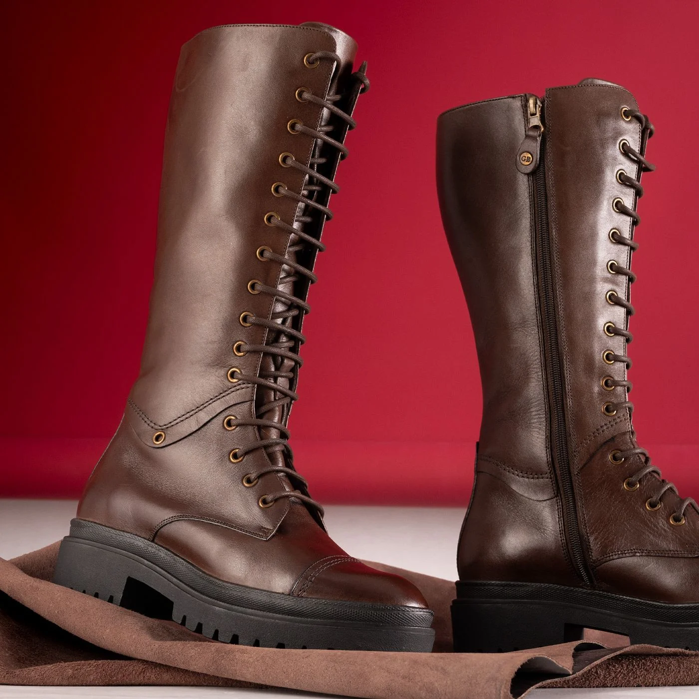 Tall leather boots on a red backdrop