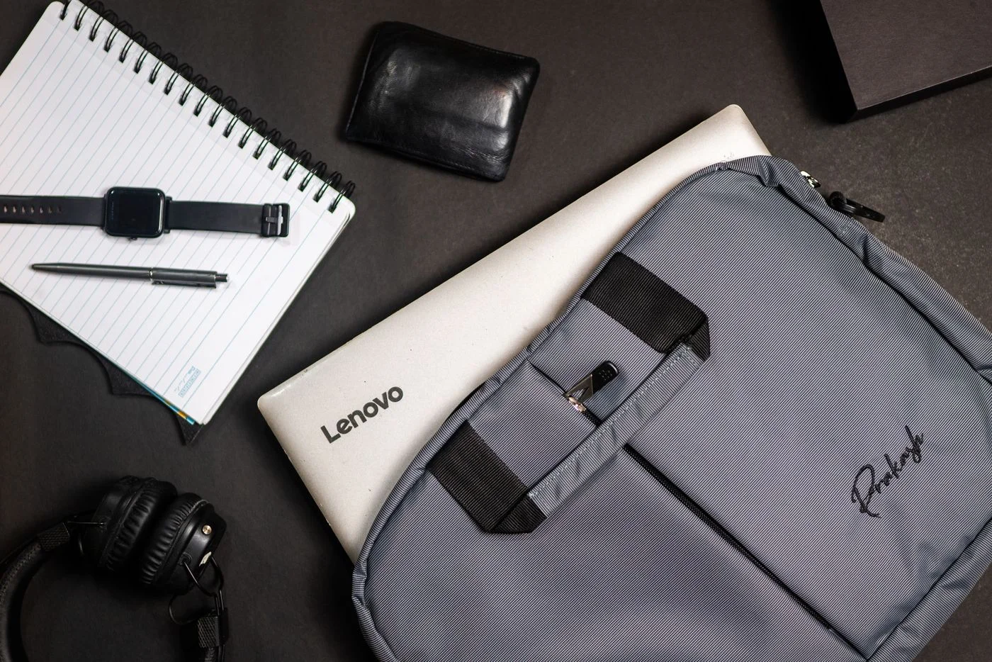 Laptop with a Bag Near a Notebook with Pen and Watch