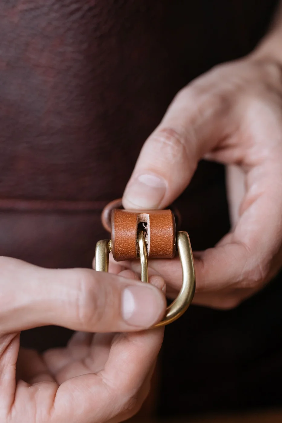 Hands holding a brown belt buckle